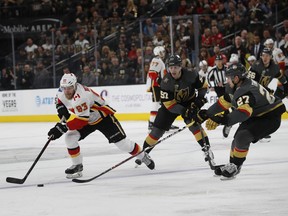 Calgary Flames center Sam Bennett (93) carries the puck past Vegas Golden Knights left wing David Perron (57) and defenseman Shea Theodore (27) during an NHL hockey game Sunday, March 18, 2018, in Las Vegas.