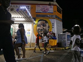 FILE - In this May 2, 2017, file photo, people congregate in front of a mural of Alton Sterling outside the Triple S Food Mart, where Sterling was killed in 2016, in Baton Rouge, La.   The investigation of the deadly police shooting that inflamed racial tensions in Louisiana's capital city has ended without criminal charges against two white officers who confronted Sterling, a black man outside a convenience store two summers ago. Experts in police tactics think the bloodshed could have been avoided if the Baton Rouge officers had done more to defuse the encounter with Sterling. They say poor police tactics and techniques may have aggravated the volatile confrontation, which lasted less than 90 seconds.