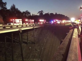 This photo provided by Jesus Tejada shows first responders looking down at a bus that plunged into a ravine, Tuesday, March 13, 2018 on Interstate 10,  Loxley, Ala. Several people were on board, and all of them were brought to 10 hospitals in Alabama and Florida, either by helicopter or ambulance, said Baldwin County Sheriff Huey Hoss Mack.  (Jesus Tejada via AP)