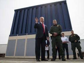 FILE - In this March 13, 2018 file photo, President Donald Trump talks with reporters as he reviews border wall prototypes in San Diego.  Trump is floating the idea of using the military's budget to pay for his long-promised border wall with Mexico.  Trump raised the idea to House Speaker Paul Ryan at a meeting last week, according to a person familiar with the discussion who spoke on condition of anonymity.