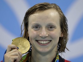 FILE - In this Aug. 9, 2016, file photo, United States' Katie Ledecky shows off her gold medal during the ceremony for the women's 200-meter freestyle final during the swimming competitions at the 2016 Summer Olympics, in Rio de Janeiro, Brazil. Ledecky is turning pro. The five-time Olympic gold medalist announced on Twitter that she is giving up her final two years of eligibility at Stanford, though she will continue to train at the West Coast school as she works toward her degree.