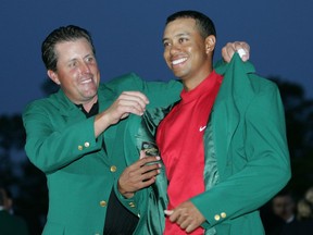 FILE - In this April 10, 2005, file photo, Tiger Woods, right, gets the Green Jacket from Phil Mickelson, left, after winning the 2005 Masters at the Augusta National Golf Club in Augusta, Ga. Tiger Woods is back for only the second time in the last five years, and what makes the sight of him at Augusta National even more tantalizing is that Woods is starting to look like the player who dominated golf for the better part of 15 years.