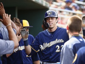 FILE - In this March 16, 2018, file photo, Milwaukee Brewers' Christian Yelich gets high-fives from teammates after scoring a run against the Cincinnati Reds during the third inning of a spring training baseball game in Goodyear, Ariz. Outfielders Lorenzo Cain and Christian Yelich are just as capable of changing games with their gloves. The two big offseason acquisitions make their Brewers debut when Milwaukee visits the San Diego Padres for their season opener on March 29.