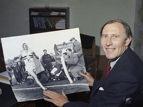 FILE - In this March 5, 1974, file photo, Dr. Roger Bannister, 45, looks back as he displays a photo of him made at Iffley, England on May 6, 1954 when he smashed the four-minute-mile barrier to clock a new record of 3:59 on a cinder track. Bannister, the first runner to break the 4-minute barrier in the mile, has died. He was 88. Bannister's family said in a statement that he died peacefully on Saturday, March 3, 2018, in Oxford "surrounded by his family who were as loved by him, as he was loved by them." (AP Photo/File)