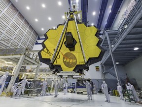 In this April 13, 2017 photo provided by NASA, technicians lift the mirror of the James Webb Space Telescope using a crane at the Goddard Space Flight Center in Greenbelt, Md. The telescope's 18-segmented gold mirror is specially designed to capture infrared light from the first galaxies that formed in the early universe. On Tuesday, March 27, 2018, NASA announced it has delayed the launch of the next-generation space telescope until 2020.