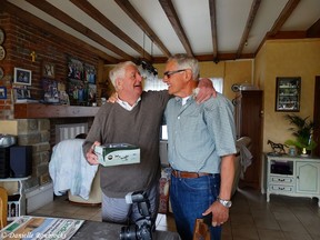 In this Aug. 10, 2016 photo provided by Danielle Roubroeks, Marc Cooche, left, and Frank Fazekas, Jr. embrace after Fazekas gave Cooche a model of the P-47 Thunderbolt fighter plane Fazekas' father was piloting when it crashed into the Cooche's family's beet field in Buysscheure, northern France in May 1944.