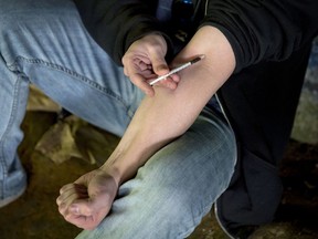 FILE - In this June 13, 2017, file photo, a man injects heroin into this arm under a bridge along the Wishkah River at Kurt Cobain Memorial Park in Aberdeen, Wash. The government said non-fatal overdoses visits to hospital emergency rooms were up about 30 percent late last summer, compared to the same three-month period in 2016. The Centers for Disease Control and Prevention reported the numbers Tuesday, March 6, 2018.