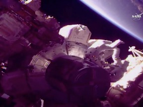In this frame from NASA TV, astronaut Drew Feustel, right, and NASA astronaut Ricky Arnold prepare to install new antennas, replace a bad camera and remove jumper cables from a leaky radiator at the International Space Station Thursday, March 29, 2018. (NASA TV via AP)