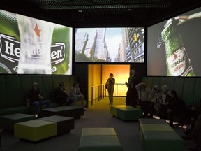 FILE- In this Dec. 9, 2008, file photo, visitors watch Heineken commercials on large screens at the Heineken Experience, Amsterdam.  Heineken has removed a commercial for its light beer after some complaints that it was racist. Hip-hop star Chance the Rapper on Sunday, March 25, 2018, tweeted the commercial was "terribly racist." In a statement, Heineken says while the ad was referencing Heineken Light, "we missed the mark."