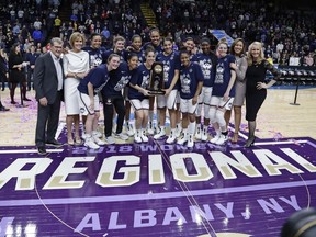 Connecticut head coach Geno Auriemma, left, poses for photographs with with his team following a women's NCAA college basketball tournament regional final game against South Carolina at the a women's NCAA college basketball tournament Monday, March 26, 2018, in Albany, N.Y. Connecticut won 94-65.
