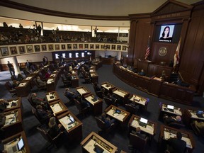 FILE - In this Feb. 21, 2018, file photo, the Florida Senate chamber is darkened while a slideshow shows each person killed in a shooting at Marjory Stoneman Douglas High School, at the state Capitol in Tallahassee, Fla. The Florida Senate spent hours debating a bill to increase school safety and restrict gun purchases in a rare Saturday session, March 3, that often turned into a debate on gun control and arming teachers in the aftermath of last month's Parkland school shootings.