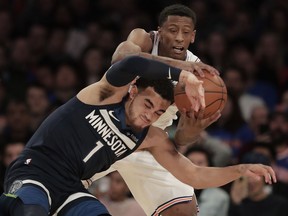 New York Knicks forward Troy Williams, top, pulls a rebound down against Minnesota Timberwolves guard Tyus Jones (1) during the second quarter of an NBA basketball game, Friday, March 23, 2018, in New York.