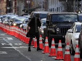 A pedestrian cuts between cars waiting in line during rush hour traffic on Hudson Street near the entrance to the Holland Tunnel, Friday, March 16, 2018, in New York. Prospects appear to be dimming for the latest proposal to impose new tolls on motorists entering the busiest parts of Manhattan. A state panel recommended tolls of as much as $11 or more as a way to address gridlock while raising money for transit. But lawmakers are balking, with some suggesting a more limited fee for taxis, limos and ride-hailing services like Uber instead.