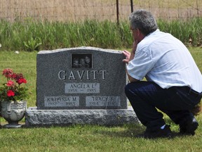 In this June 6, 2012 photo provided by John Masson, David Gavitt visits the grave of his wife and two daughters in Ionia County, Mich., immediately after he was released from prison after 26 years. Gavitt was convicted of arson and murder in their 1985 deaths, but the convictions were overturned after scientists took a new look at evidence from the house fire. Gavitt now is seeking compensation under a Michigan law that pays people who were wrongly convicted.