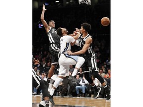 Memphis Grizzlies guard Andrew Harrison (5) loses the ball as he collides with Brooklyn Nets guard Caris LeVert, left, and Nets guard Spencer Dinwiddie (8) while driving to the basket during the first half of an NBA basketball game, Monday, March 19, 2018, in New York.
