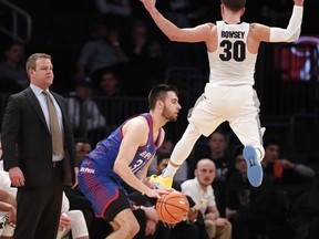 Marquette head coach Steve Wojciechowski, left, watches, as Marquette guard Andrew Rowsey (30) leaps in front of DePaul guard Max Strus (31) during the first half of an NCAA college basketball game in the first round of the Big East conference tournament, in New York, Wednesday, March, 7, 2018.