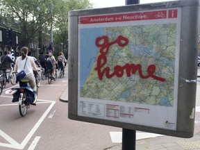 FILE - In this May 11, 2016, file photo, graffiti reading "Go Home" is sprayed on a map of bicycle paths at the entrance to Amsterdam's Vondelpark, a popular spot for tourists to ride their rental bicycles. Experts from GetYourGuide say travelers can reduce their impact on heavily touristed sites by booking visits in advance for less popular times, by traveling in off-peak seasons and by seeking out smaller, more authentic experiences where they can live like a local.