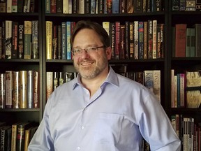 In this undated photo Nathan Shafer, a life-long book collector, poses in front of his bookshelf in Arvada, Colo. Shafer said he feels there is no point to a backwards-facing bookshelf. "That's not what books are for," he said.