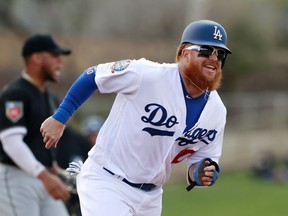 FILE - In this Friday, Feb. 23, 2018, file photo, Los Angeles Dodgers' Justin Turner runs to third from second after a throwing error by Chicago White Sox second baseman Yoan Moncada during the third inning of a baseball spring exhibition game, in Glendale, Ariz. Turner has a broken left wrist after being hit by a pitch during a spring training game, Monday, March 19, 2018.
