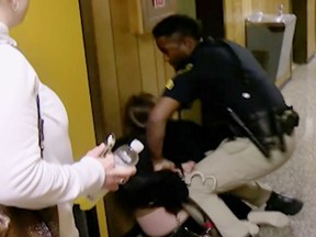 FILE - In this Monday, Jan. 8, 2018, file image made from a video provided by KATC-TV middle-school English teacher Deyshia Hargrave is handcuffed by a city marshal after complying with a marshal's orders to leave a Vermilion Parish School Board meeting in Abbeville, La., west of New Orleans. Louisiana's attorney general sued a local school board Thursday, March 8, 2018, over a meeting disrupted by the video-recorded arrest of Hargrave being roughly handcuffed on a hallway floor after she criticized the district superintendent's pay raise.  Attorney General Jeff Landry's lawsuit accuses the Vermilion Parish School Board and its members of violating the state's Open Meetings Law by stifling public debate at the Jan. 8 meeting. (KATC-TV via AP, File)