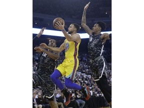 Golden State Warriors guard Stephen Curry (30) shoots between San Antonio Spurs forward LaMarcus Aldridge (12) and guard Dejounte Murray (5) during the first half of an NBA basketball game in Oakland, Calif., Thursday, March 8, 2018.