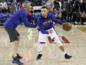 Golden State Warriors guard Stephen Curry, right, warms up with assistant coach Bruce Fraser before the team's NBA basketball game against the Atlanta Hawks in Oakland, Calif., Friday, March 23, 2018.