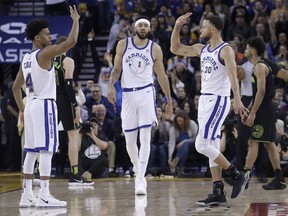 Golden State Warriors guard Stephen Curry (30) celebrates after scoring, with guard Quinn Cook (4) and center JaVale McGee (1) during the second half of an NBA basketball game against the Atlanta Hawks in Oakland, Calif., Friday, March 23, 2018.