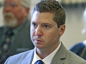 FILE – In this June 8, 2017, file pool photo, Ray Tensing listens to a prosecutor's opening statement during the former University of Cincinnati police officer's retrial at the Hamilton County Courthouse in Cincinnati. The University of Cincinnati has agreed to pay some $344,000 in back wages and legal fees to a white police officer the school fired after he fatally shot a black unarmed motorist. The school announced the settlement Thursday, March 22, 2018, of a union grievance brought on behalf of Tensing for his 2015 firing following his indictment on murder charges. The charges were dropped last year after two juries deadlocked.
