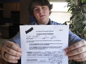 Jacob Shoemaker, 18, holds a copy of his school suspension slip at his home, March 16, 2018, in Hilliard, Ohio. An Ohio high school student says he tried to remain nonpolitical during school walkouts over gun violence and was suspended for a day because he stayed in a classroom instead of joining protests or the alternative, a study hall. Hilliard senior Jacob Shoemaker's citation for not following instructions was shared online, prompting a flood of angry messages to the phone number it had for his father. Some people thought Jacob was suspended for walking out, or mistook his father for the principal.