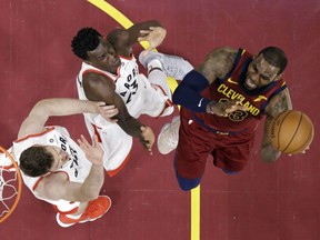 Toronto Raptors' Jakob Poeltl, left, and Pascal Siakam defend against Cleveland Cavaliers' LeBron James during the first half of an NBA basketball game Wednesday, March 21, 2018, in Cleveland.