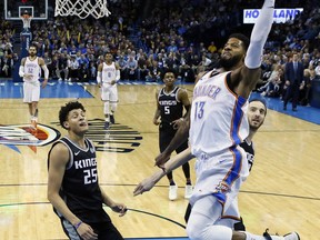 Oklahoma City Thunder forward Paul George (13) shoots in front of Sacramento Kings forward Justin Jackson (25), guard De'Aaron Fox (5) and center Kosta Koufos, right, in the first half of an NBA basketball game in Oklahoma City, Monday, March 12, 2018.