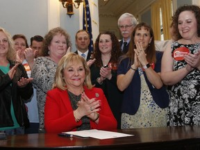 Surrounded by teachers and legislators, Oklahoma Gov. Mary Fallin applauds after signing a teacher pay raise bill in Oklahoma City, Thursday, March 29, 2018.