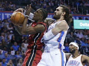 Miami Heat forward Josh Richardson, left, reaches for a rebound in front of Oklahoma City Thunder center Steven Adams, center, during the first half of an NBA basketball game in Oklahoma City, Friday, March 23, 2018.