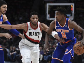 New York Knicks guard Frank Ntilikina tries to get past Portland Trail Blazers forward Evan Turner as Knicks center Enes Kanter watches during the first half of an NBA basketball game in Portland, Ore., Tuesday, March 6, 2018.