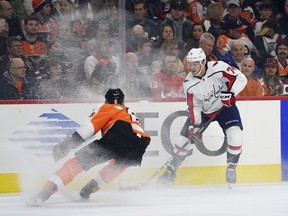 Washington Capitals' John Carlson, right, controls the puck past Philadelphia Flyers' Travis Sanheim during the first period of an NHL hockey game, Sunday, March 18, 2018, in Philadelphia.