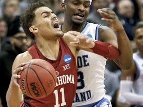 Oklahoma's Trae Young (11) tries to get past Rhode Island's Stanford Robinson during the first half of an NCAA men's college basketball tournament first-round game, Thursday, March 15, 2018, in Pittsburgh.