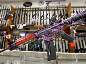 A Smith & Wesson M&P 15-22 Muddy Girl Sport rifle chambered in .22 LR is shown in front of a rack of other rifles at Duke's Sport Shop in New Castle, Pa. on Thursday, March 1, 2018. Sales of firearms slowed dramatically after the election of President Donald Trump in 2016. American Outdoor Brands, which owns Smith & Wesson, said revenue fell by one-third over the past three months. The company said demand dropped in December and January, before the shootings in Parkland, Florida, and the debates on gun laws that followed. The company doesn't expect sales to improve much over the next 18 months.