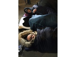 In this photo taken on Wednesday, Feb. 28, 2018, Abdelsalem Hitache, deputy mayor of Le Blanc Mesnil, front, sleeps in the street  in Paris. Braving an Arctic blast sweeping across Europe, about two dozen officials from the Paris region have spent a frigid night outdoors to call attention to the plight of the homeless.