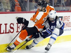Philadelphia Flyers' Andrew MacDonald, left, and Winnipeg Jets' Mathieu Perrault vie for the puck during the first period of an NHL hockey game Saturday, March 10, 2018, in Philadelphia.