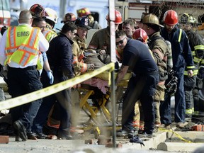 Emergency personnel move an injured firefighter to an ambulance after a wall collapse at the scene of a fire in York, Pa., Thursday, March 22, 2018. York officials said part of the four-story building fell on firefighters as they were looking for hot spots and investigating the cause of the fire that broke out Wednesday at the Weaver Organ and Piano factory.