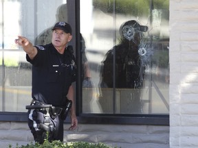 FILE--In this Sept. 6, 2011, file photo, with bullet holes seen in a window, officers look for evidence at the scene of a shooting at an IHOP restaurant in Carson City, Nev. Recent mass shootings spurred Congress to try to improve the background check system used during gun purchases, but experts say the system is so fractured that federal legislation being considered in Washington D.C. will do little to help keep weapons out of the hands of dangerous people.