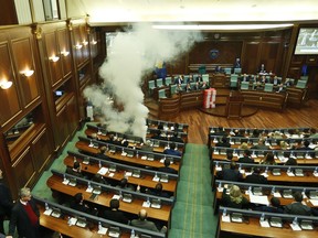 Opposition lawmakers release a tear gas canister disrupting a parliamentary session in Kosovo capital Pristina on Wednesday, March 21, 2018. Kosovo's Parliament, has temporarily suspended its session after tear gas disrupted the vote on a border demarcation deal with Montenegro.