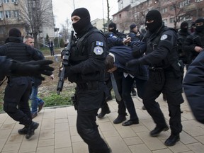 Kosovo police escort Marko Djuric a Serb official to a police station in Kosovo capital Pristina after he was arrested in northern Kosovo town of Mitrovica on Monday, March 26, 2018. Kosovo police arrested a Serb official after he was banned from visiting a divided town in northern Kosovo and then fired tear gas and stun grenades at Serb protesters Monday.