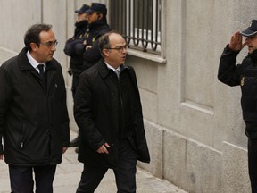 Catalan president candidate Jordi Turull, center and former cabinet member Josep Rull are saluted by a national police officer on arrival at the Supreme Court in Madrid, Friday, March 23, 2018. A Spanish Supreme Court probe into last year's attempt to secede Catalonia from Spain wraps Friday with the judge issuing indictments and possible rebellion and other charges for various regional politicians and separatist leaders and signaling that he may issue for the latter preventive measures that could include pre-trial jailing.