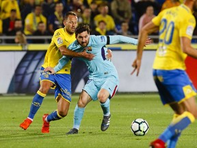 CORRECTING YEAR TO 2018 - FC Barcelona's Messi, centre, is held by Las Palmas' Dani Castellano, left, during a Spanish La liga soccer match at the Gran Canaria stadium in the Canary island of Las Palmas, Thursday March 1, 2018.