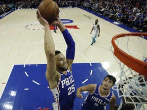 Philadelphia 76ers' Ben Simmons (25) goes up for a dunk as Dario Saric (9) and Charlotte Hornets' Michael Kidd-Gilchrist (14) look on during the first half of an NBA basketball game, Monday, March 19, 2018, in Philadelphia.