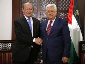 French Foreign Minister Jean-Yves Le Drian, left, shakes hands with Palestinian President Mahmoud Abbas, in the West Bank city of Ramallah, Monday, March 26, 2018.