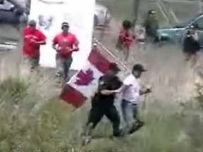 Randy Fleming is arrested - purportedly to prevent trouble - by OPP officers for carrying a Canadian flag in Caledonia, Ont., in an image taken from a video shown in court.
