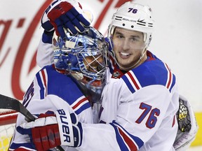 Brady Skjei, right, of the New York Rangers, has a hug for goaltender Henrik Lundqvist following his 50-save performance in a 3-1 victory over the Calgary Flames in NHL action Friday at the Scotiabank Saddledome.