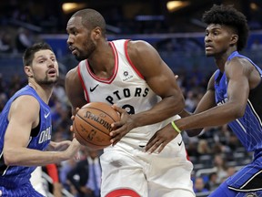 Toronto Raptors' Serge Ibaka prepares to move toward the basket between the Magic's Nikola Vucevic, left, and Jonathan Isaac during the first half of their game, Tuesday night in Orlando, Fla.